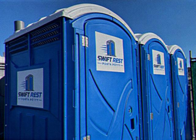 Row of portable restroom units lined up on a construction site